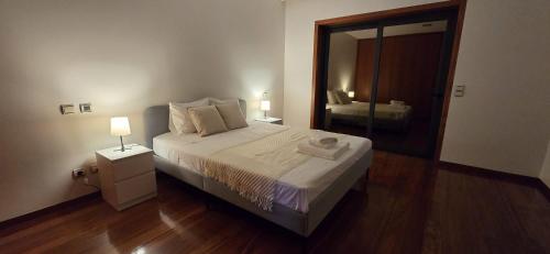 a bedroom with a large bed and a mirror at Petit Maison in Além da Ribeira