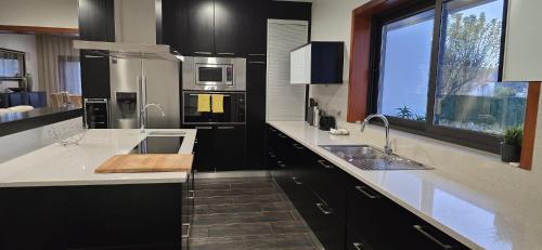 a kitchen with black cabinets and white counter tops at Petit Maison in Além da Ribeira