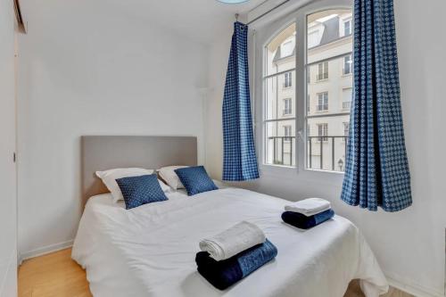 a bedroom with a bed with blue curtains and a window at Accommodation closest to Disneyland in Serris