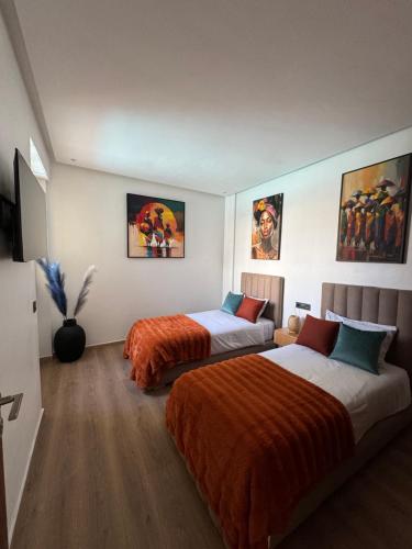 ein Hotelzimmer mit 2 Betten und Gemälden an den Wänden in der Unterkunft Prestige stay with swimming pool in Agadir