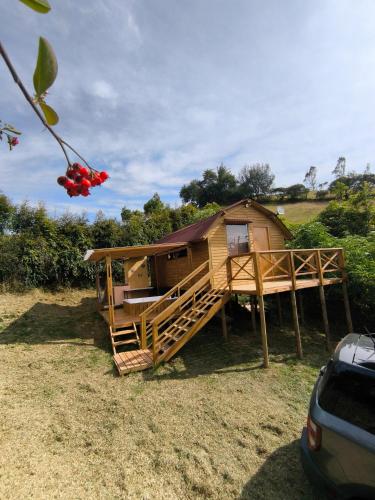 a tree house with a deck and a car at Glamping con jacuzzi La Terraza del cielo in Chocontá