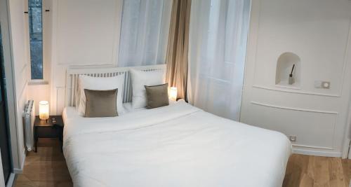 une chambre avec un grand lit blanc avec des oreillers dans l'établissement Appartement -Paris Bastille LIGHT, à Paris