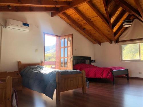 a bedroom with two beds and a large window at Cabaña EL GALLO in Villa General Belgrano
