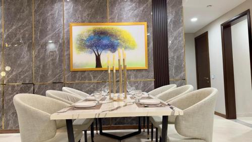 a dining room with a table with chairs and a painting at Luxury One Bed Apartment Goldcrest Grand Mall and Residency DHA LHR in Lahore