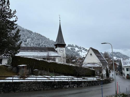 a church with a clock tower in a town at Chalet Finkenwiese in Zweisimmen