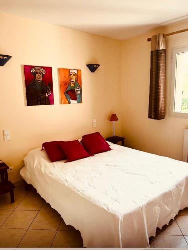 une chambre avec un lit blanc avec deux tableaux au mur dans l'établissement Villa indépendante avec piscine, à San-Gavino-di-Carbini