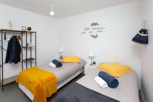 two beds with yellow and blue sheets in a room at L Escale in Ports