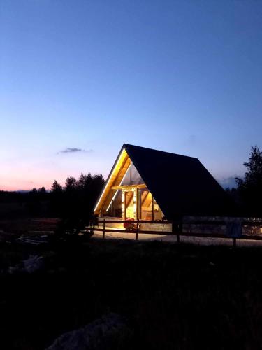a glass house with a triangular roof at dusk at Villas Sunny Hill in Žabljak
