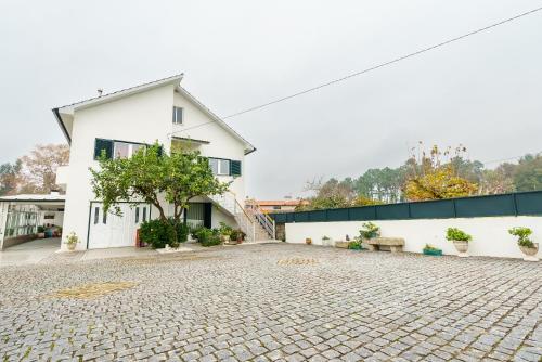 a white building with a tree on a cobblestone street at Casa O Limoeiro - Charming Village Apartment in Ponte de Lima
