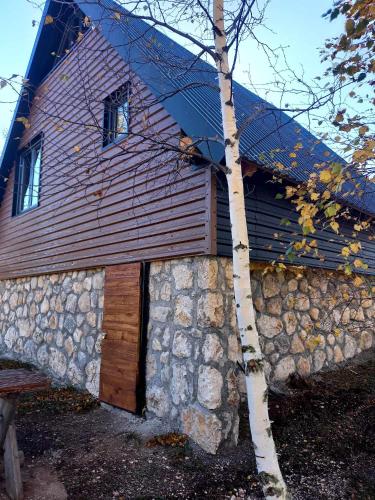 a building with a stone wall and a wooden door at Villas Sunny Hill in Žabljak