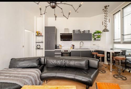 un salon avec un canapé en cuir et une cuisine dans l'établissement Chic Stay near Louvre & Eiffel Tour, à Paris