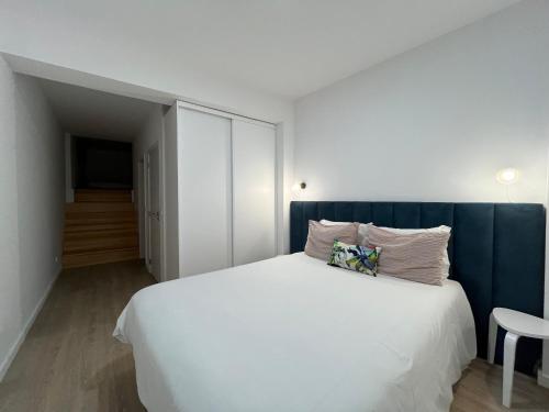 a bedroom with a white bed with a blue headboard at Romantic Downtown Studio in Vila do Conde