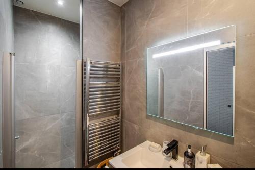 une salle de bain avec un lavabo, une douche et un miroir dans l'établissement Chic Stay near Louvre & Eiffel Tour, à Paris