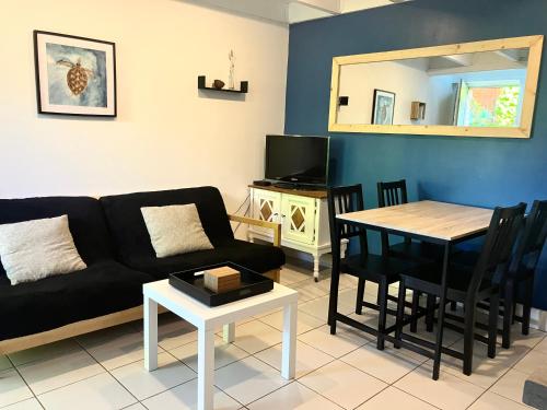 un salon avec un canapé noir et une table dans l'établissement Appartement proche de la mer, à Clohars-Carnoët