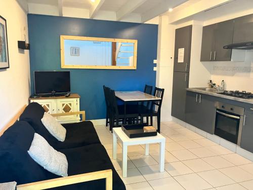 un salon avec un canapé et une table et une cuisine dans l'établissement Appartement proche de la mer, à Clohars-Carnoët