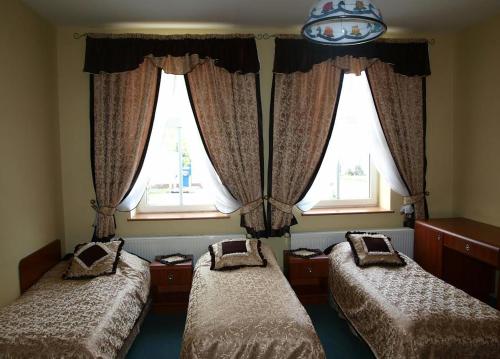 two beds in a room with two windows at Hotel Okatex in Żagań
