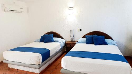 two beds sitting next to each other in a bedroom at Hotel Iguanas in Yautepec