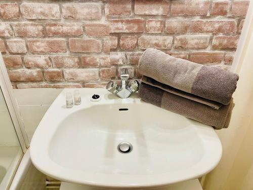 La salle de bains est pourvue d'un lavabo blanc et d'un mur en briques. dans l'établissement Studio Palais des Congrès Maillot Paris, à Paris