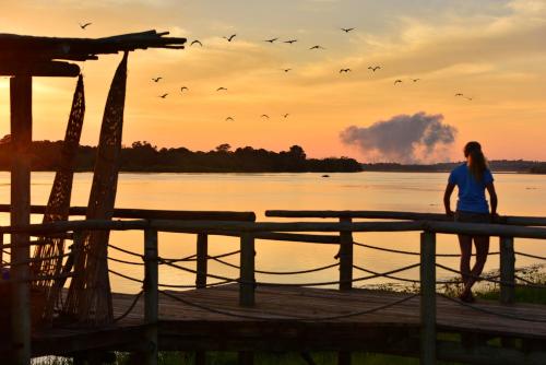 a woman standing on a dock near the water with birds at Victoria Falls River Lodge in Victoria Falls