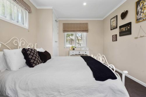 a bedroom with a white bed with black pillows at Charming 3 Bedroom Family Home Pet Friendly in Hamilton