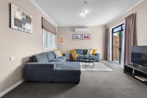 a living room with a blue couch and a tv at Charming 3 Bedroom Family Home Pet Friendly in Hamilton