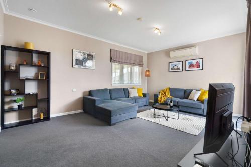 a living room with two blue couches and a tv at Charming 3 Bedroom Family Home Pet Friendly in Hamilton