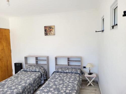 two beds in a room with a white wall at La Serena in María Grande