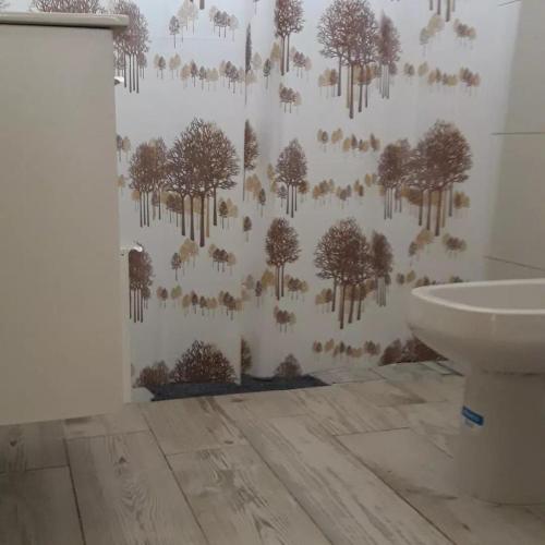 a bathroom with a wall with trees and a toilet at La Serena in María Grande