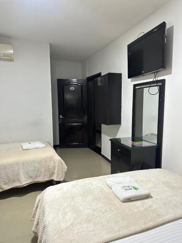 a room with two beds and a flat screen tv at Hotel Palmeras De Mariana in Bucaramanga