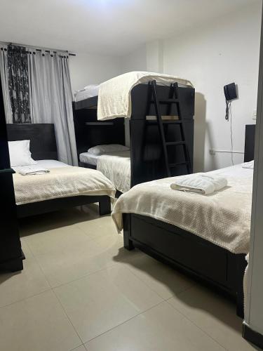 a room with two beds and a chair in it at Hotel Palmeras De Mariana in Bucaramanga