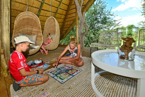 three children sitting on the floor in a gazebo playing a game at Victoria Falls River Lodge in Victoria Falls