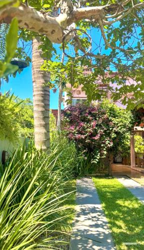 a walkway in front of a house with pink flowers at Pousada Origin in Guarda do Embaú