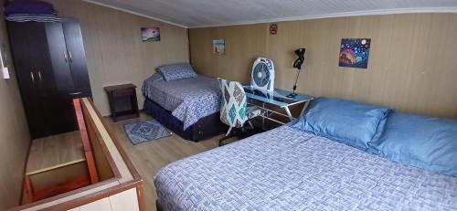 1 dormitorio con 2 camas y escritorio con escritorio en Cabañas Los Geranios, en Osorno