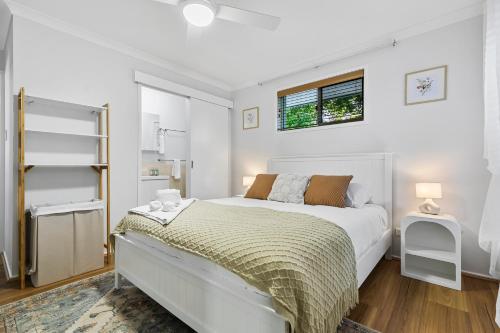 a white bedroom with a bed and a window at La Costa! in Bongaree