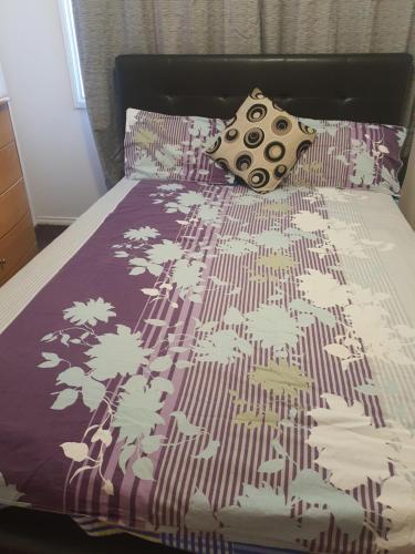 a bed with a purple comforter and a pillow on it at Home stay in Wyndham Vale
