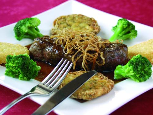 a plate of food with meat and broccoli on a table at Gasthof-Hotel Dilger in Rattenberg