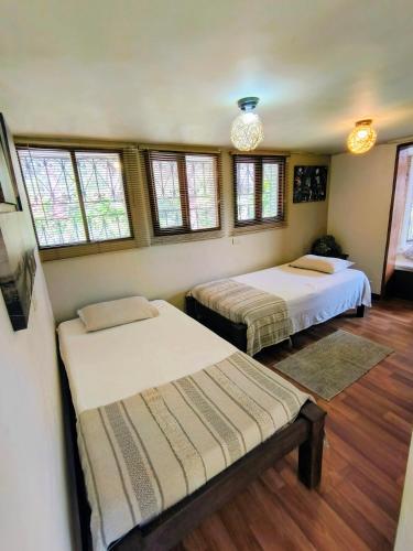 two beds in a room with windows and wooden floors at Hermosa Finca El Castillo - Excelente Ubicación Rionegro Marinilla in Rionegro