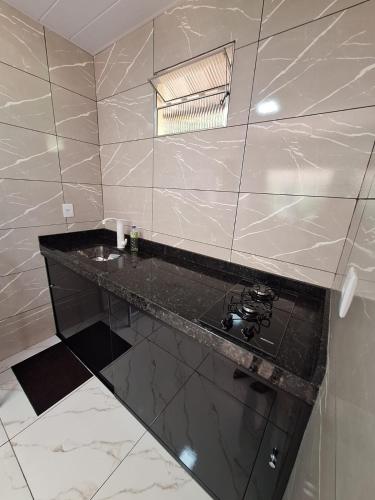 a bathroom with a black counter and a sink at Chalé Roda Dágua B in Alto Caparao