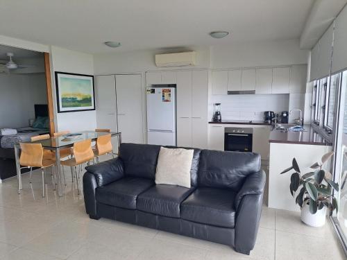a living room with a black couch and a table at Oshen Holiday Apartments Yeppoon in Yeppoon
