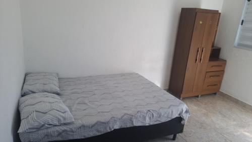 a bedroom with a bed and a wooden cabinet at Kitnets Oceanos in Caraguatatuba