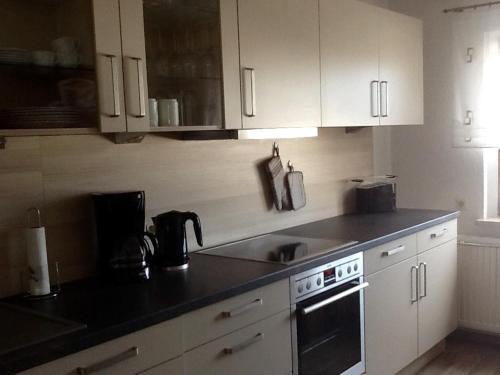 a kitchen with white cabinets and a black counter top at Ferienhaus Günther in Aue