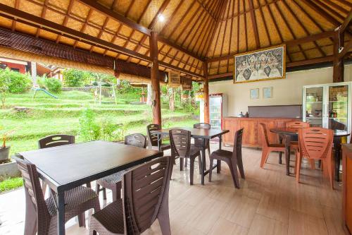 a dining room with tables and chairs and a kitchen at Pondok Hari Baik in Balian