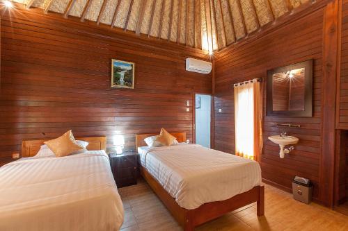 a bedroom with two beds and a sink in it at Pondok Hari Baik in Balian