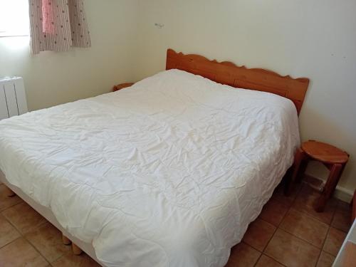 une chambre avec un lit blanc avec une tête de lit en bois dans l'établissement Central apartment with mountain view, à Val Cenis