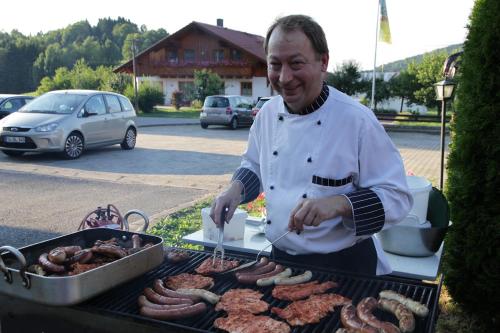 a man cooking sausages and meat on a grill at Gasthof-Hotel Dilger in Rattenberg