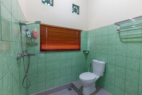 a green bathroom with a toilet and a shower at Pondok Hari Baik in Balian