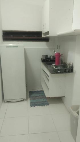 a white kitchen with a stove and a refrigerator at Studio 4 pessoas in Salvador