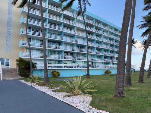 a large building with palm trees in front of it at Ocean view Studio Marina Lanais in Fajardo