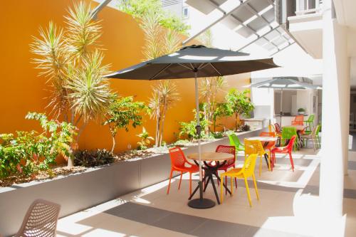 a patio with a table and chairs and an umbrella at Oshen Holiday Apartments Yeppoon in Yeppoon