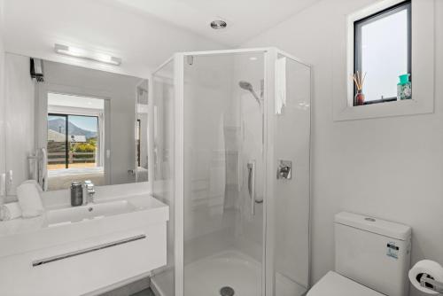 a white bathroom with a shower and a sink at The Alpine Patch - Wanaka Holiday Home in Wanaka